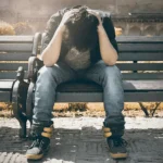 A man sits on a bench, his head in his hands. He is addicted to pornography and doesnt know the way out