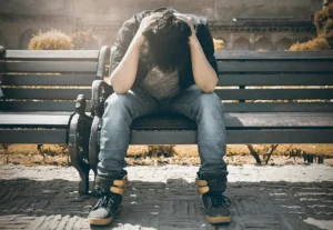A man sits on a bench, his head in his hands. He is addicted to pornography and doesnt know the way out